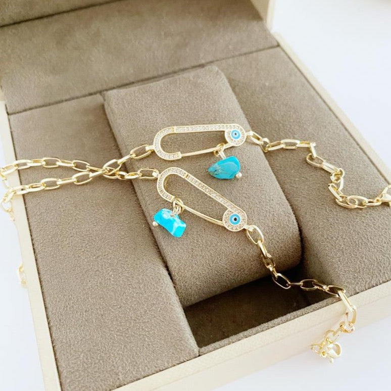 Evil Eye Bracelet featuring a gold chain and zircon safety pin charm, elegantly designed for protection and style.