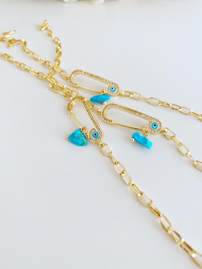 Evil Eye Bracelet featuring a gold chain and zircon safety pin charm, elegantly designed for protection and style.