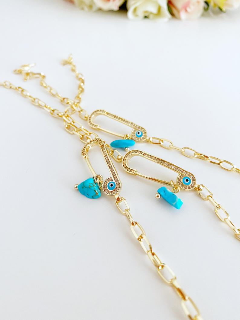 Evil Eye Bracelet featuring a gold chain and zircon safety pin charm, elegantly designed for protection and style.