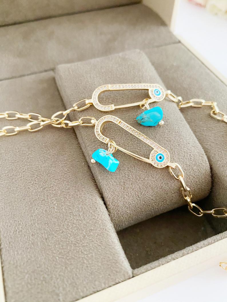 Evil Eye Bracelet featuring a gold chain and zircon safety pin charm, elegantly designed for protection and style.