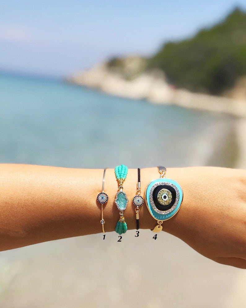 Evil Eye Bracelet Set featuring gold bangles and turquoise hamsa charm, showcasing adjustable design and handmade craftsmanship.