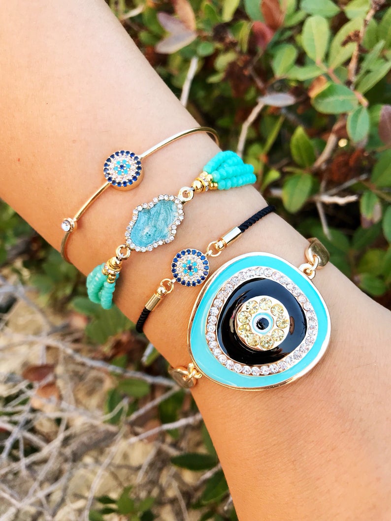 Evil Eye Bracelet Set featuring gold bangles and turquoise hamsa charm, showcasing adjustable design and handmade craftsmanship.