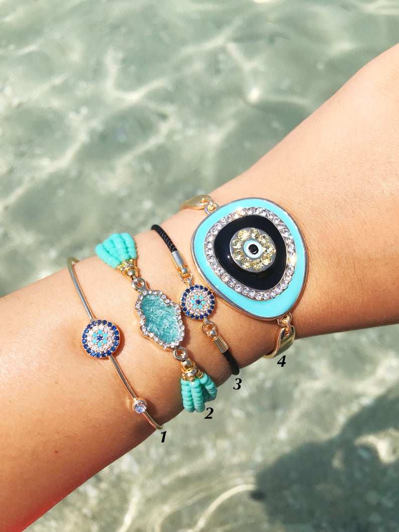 Evil Eye Bracelet Set featuring gold bangles and turquoise hamsa charm, showcasing adjustable design and handmade craftsmanship.