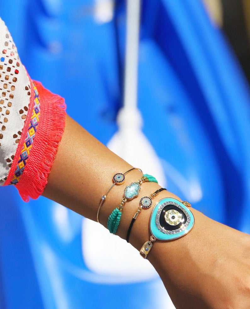 Evil Eye Bracelet Set featuring gold bangles and turquoise hamsa charm, showcasing adjustable design and handmade craftsmanship.