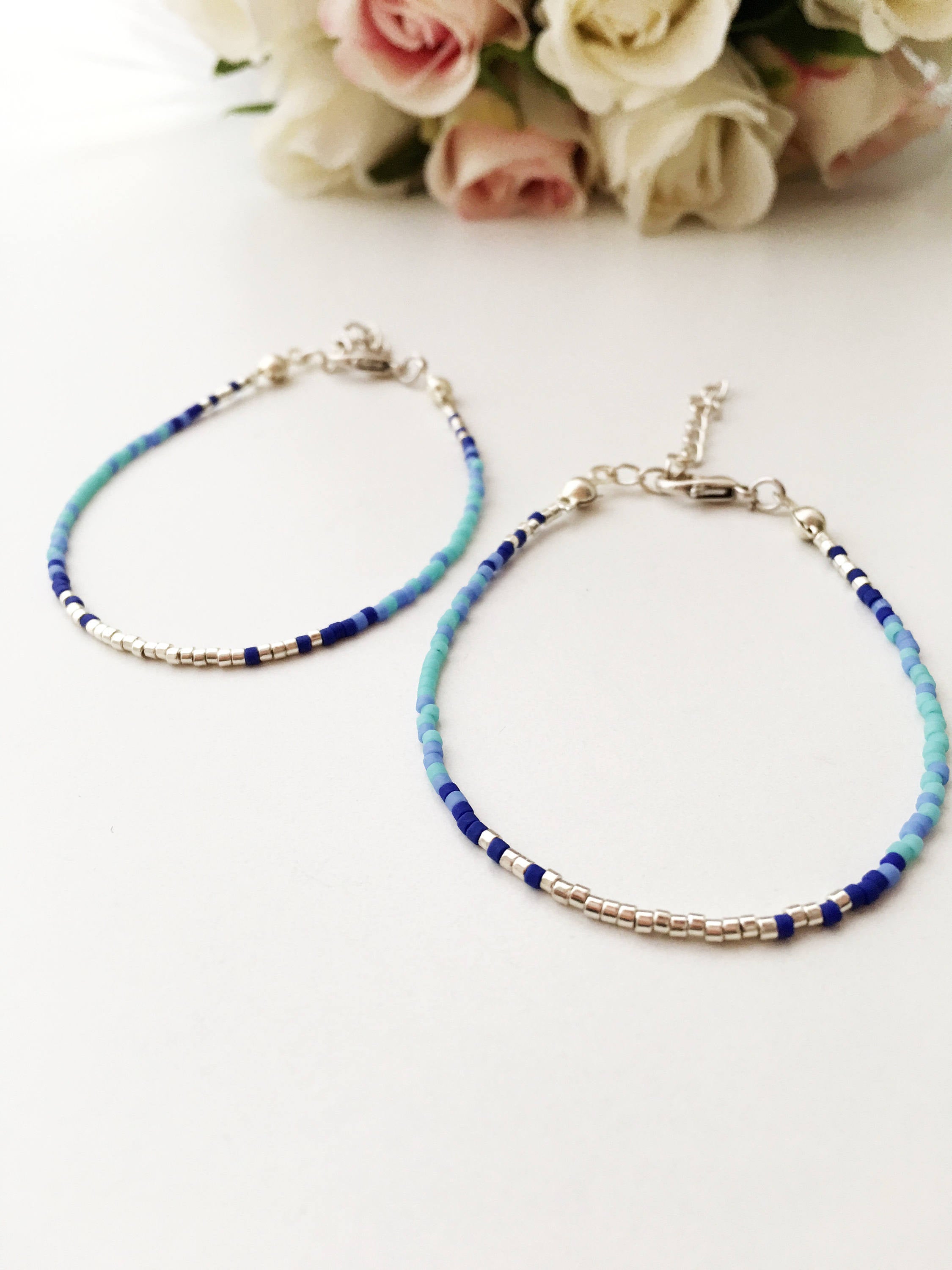 A collection of handmade silver evil eye bracelets featuring various designs including safety pin, beaded, and zirconia styles.