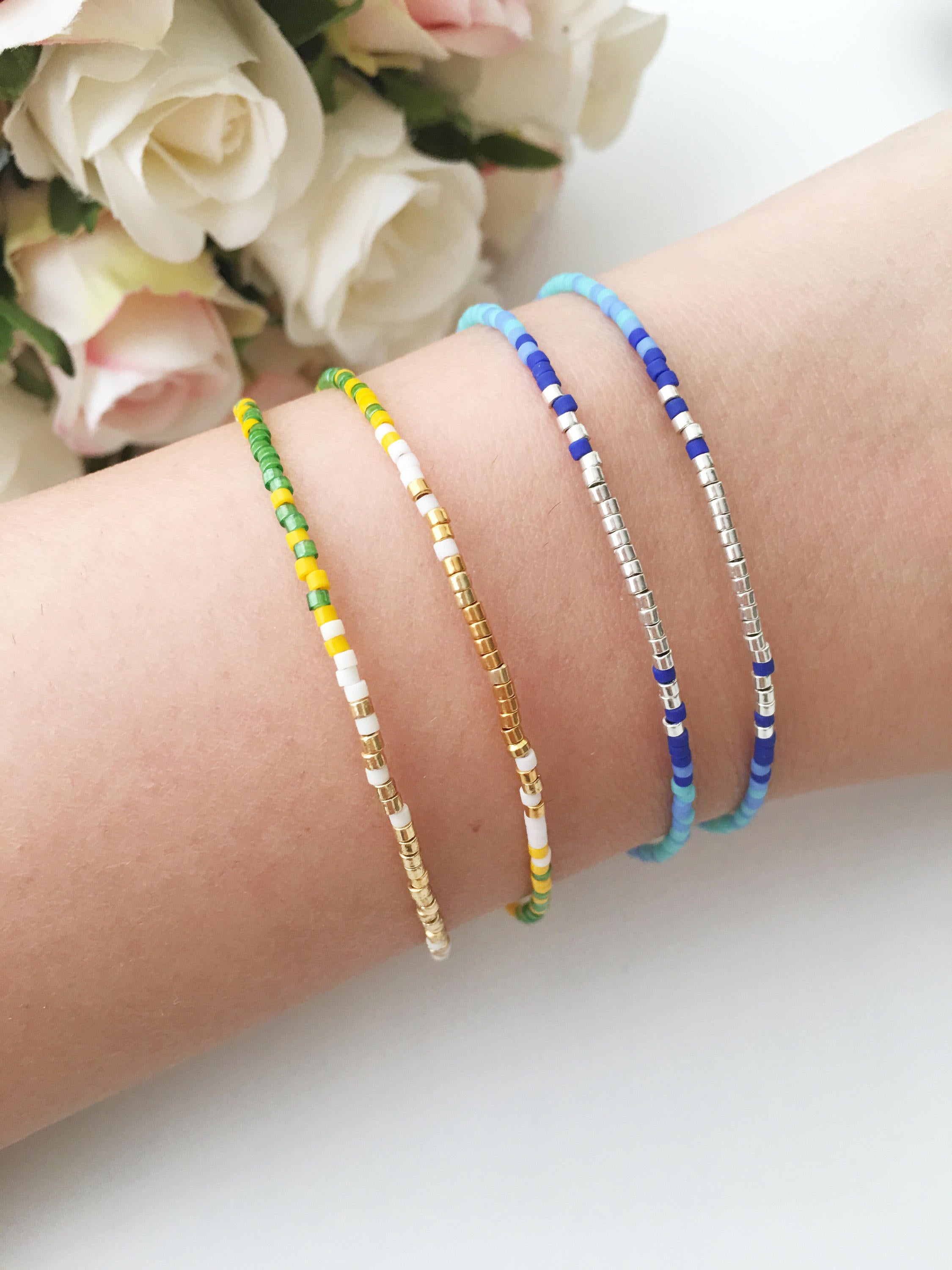 A collection of handmade silver evil eye bracelets featuring various designs including safety pin, beaded, and zirconia styles.