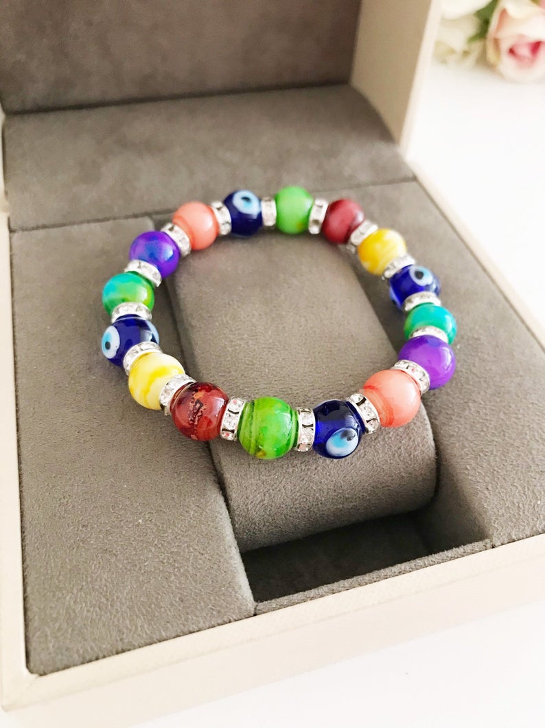 A colorful stretchable Evil Eye Bracelet featuring vibrant rainbow beads and a central blue glass evil eye bead.