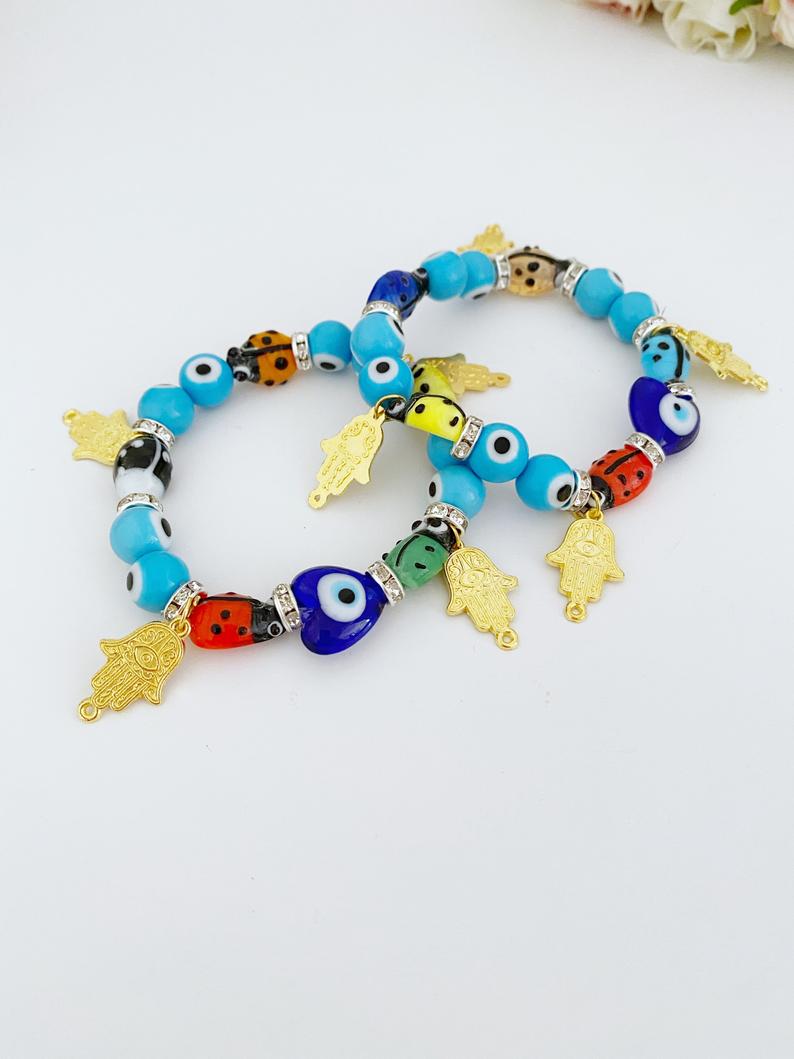 Evil Eye Bracelet featuring turquoise beads, gold hamsa charm, and ladybug charm, showcasing a stylish and protective design.