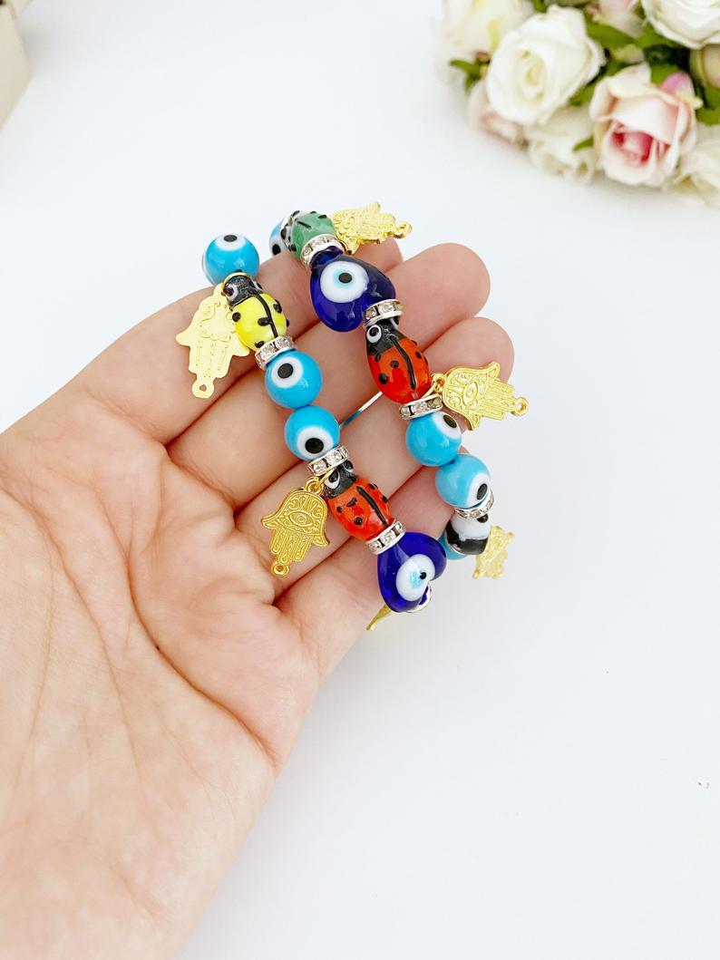 Evil Eye Bracelet featuring turquoise beads, gold hamsa charm, and ladybug charm, showcasing a stylish and protective design.