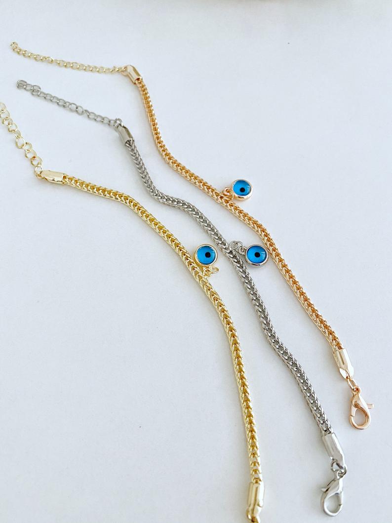 Evil Eye Chain Bracelet featuring a blue evil eye bead on a rose gold Byzantine chain, showcasing intricate design and elegance.