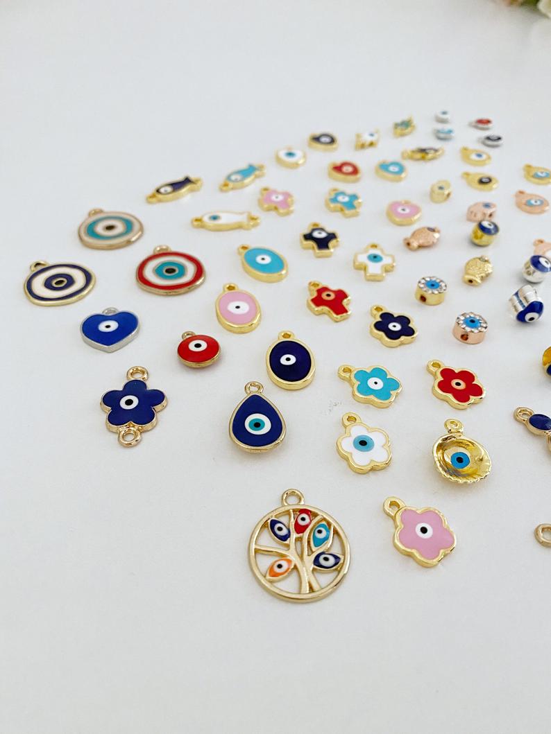 A collection of 63 different styles of evil eye charms in bulk, featuring gold, silver, and enamel designs.