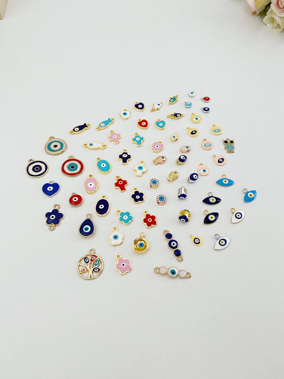 A collection of 63 different styles of evil eye charms in bulk, featuring gold, silver, and enamel designs.