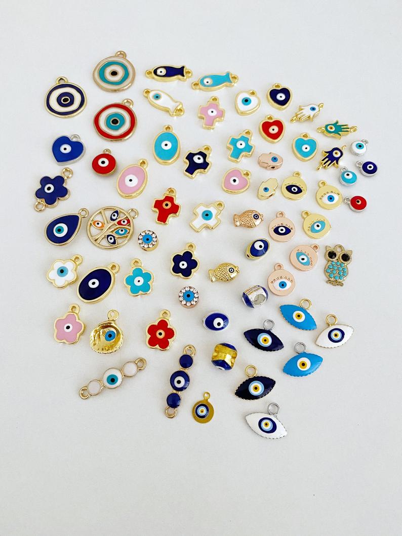 A collection of 63 different styles of evil eye charms in bulk, featuring gold, silver, and enamel designs.