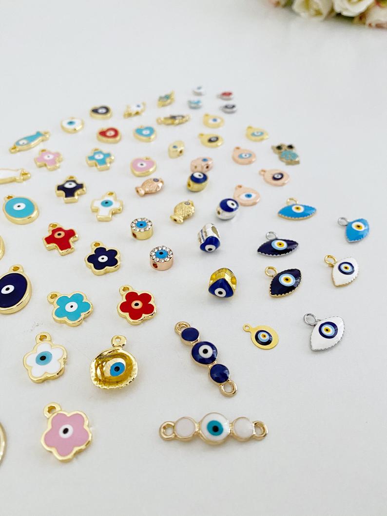 A collection of 63 different styles of evil eye charms in bulk, featuring gold, silver, and enamel designs.