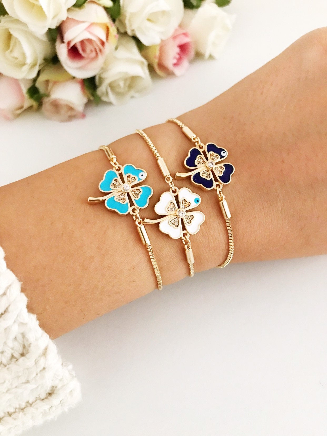 Handmade adjustable gold Evil Eye Clover Bracelet featuring a clover charm and tiny evil eye, available in multiple colors.