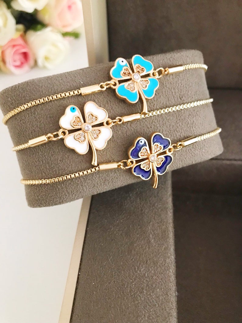 Handmade adjustable gold Evil Eye Clover Bracelet featuring a clover charm and tiny evil eye, available in multiple colors.
