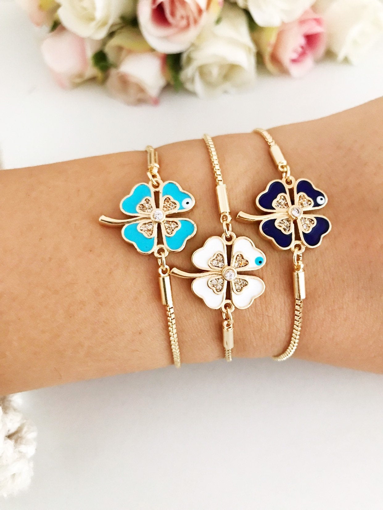 Handmade adjustable gold Evil Eye Clover Bracelet featuring a clover charm and tiny evil eye, available in multiple colors.