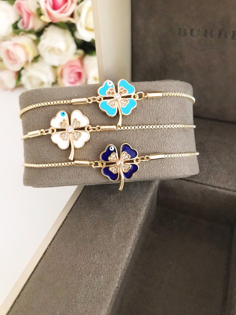 Handmade adjustable gold Evil Eye Clover Bracelet featuring a clover charm and tiny evil eye, available in multiple colors.