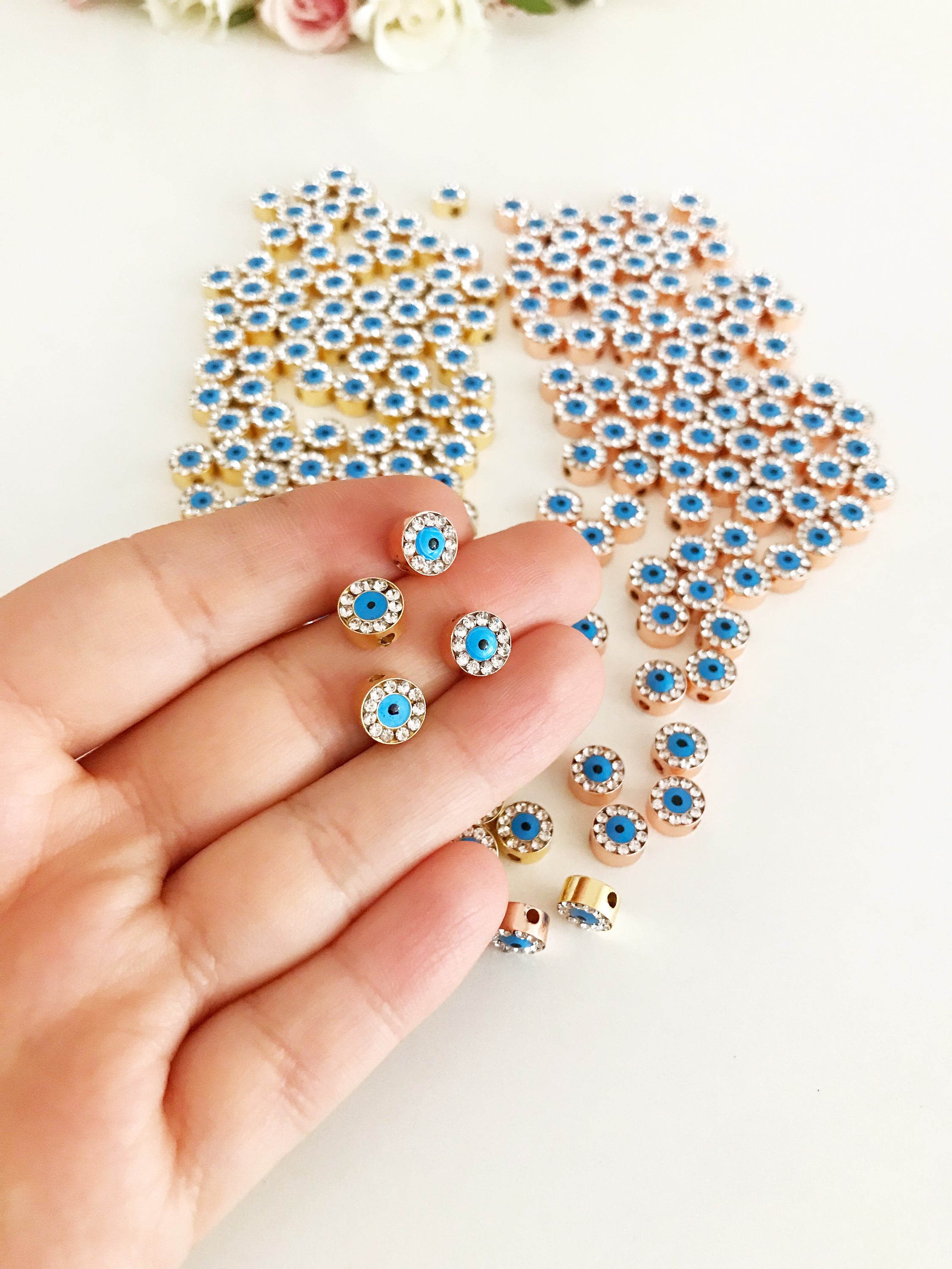 Evil Eye Connector Charm in gold and rose gold finishes, featuring a protective evil eye design, ideal for jewelry making.