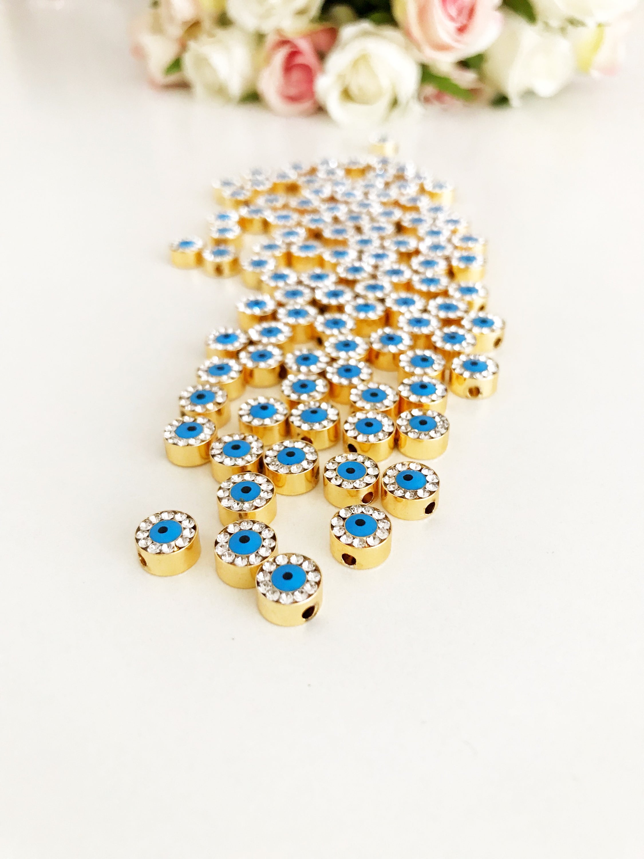 Evil Eye Connector Charm in gold and rose gold finishes, featuring a protective evil eye design, ideal for jewelry making.