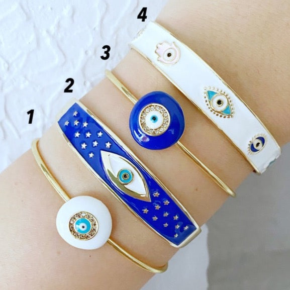 Evil Eye Cuff Bracelet featuring a movable blue evil eye charm on a gold stainless steel bangle, showcasing its elegant design and adjustable fit.