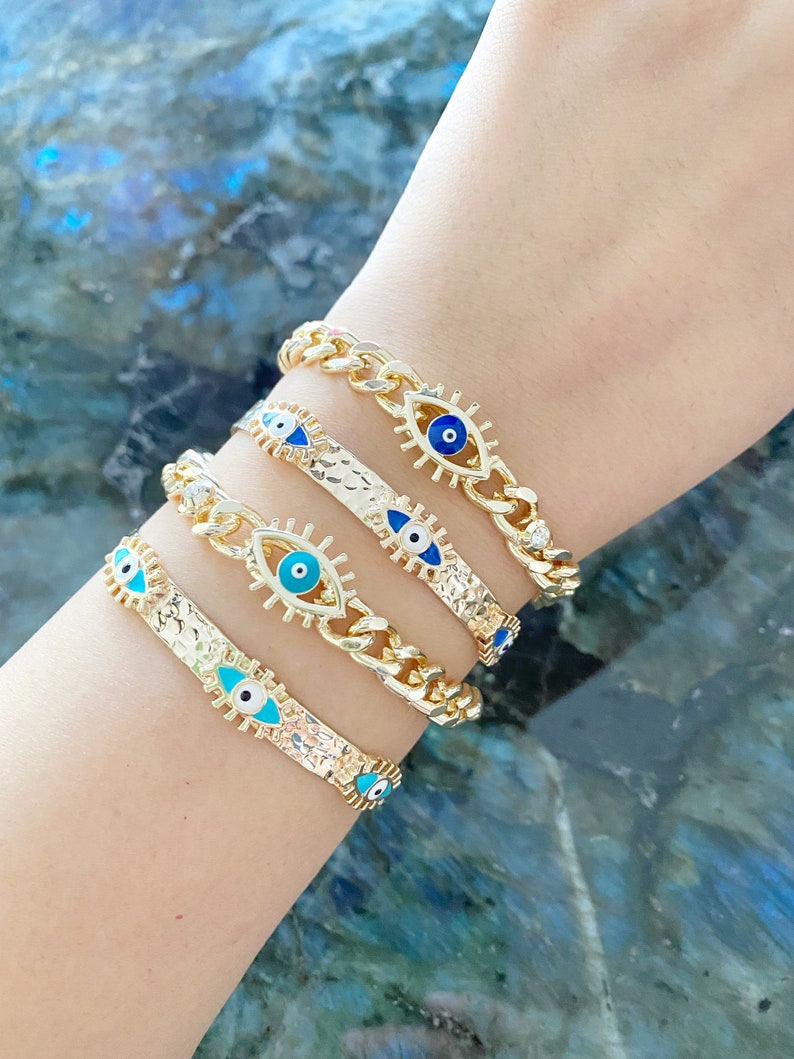 Gold Evil Eye Cuff Bracelet featuring a movable blue evil eye charm, adjustable design, and tarnish resistant stainless steel material.