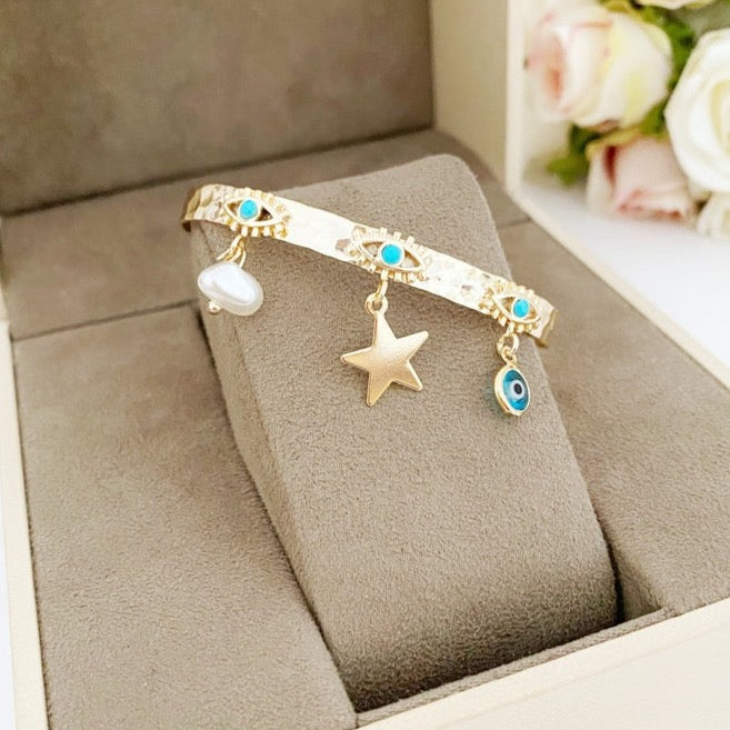 Evil Eye Cuff Bracelet featuring gold color, star, pearl, and blue eye charms, showcasing a stylish and waterproof design.