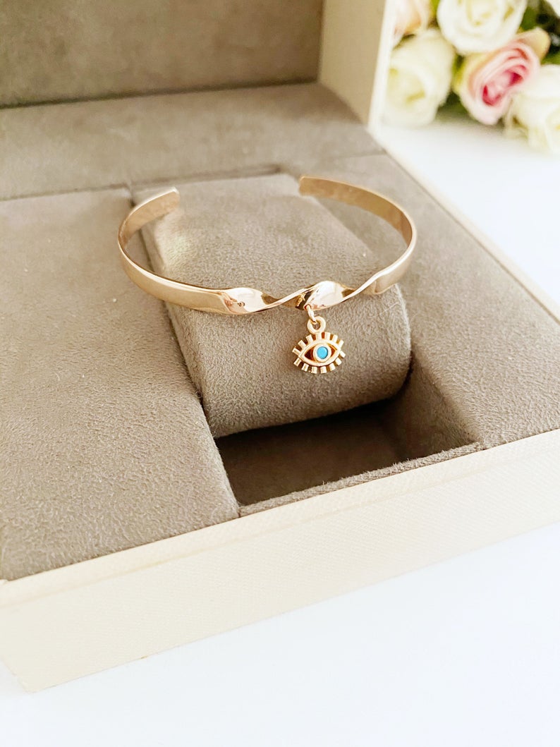 Elegant Evil Eye Cuff Bracelet in rose gold and silver, featuring a movable evil eye charm, crafted from tarnish-resistant stainless steel.