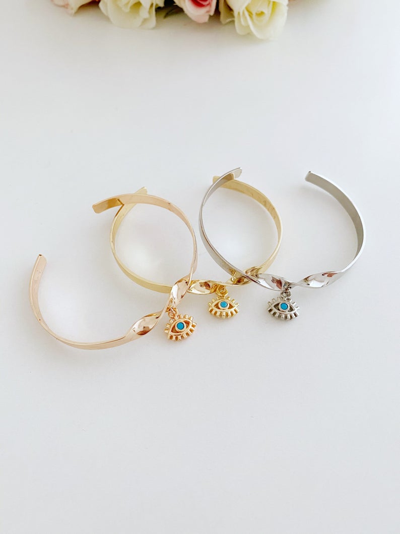 Elegant Evil Eye Cuff Bracelet in rose gold and silver, featuring a movable evil eye charm, crafted from tarnish-resistant stainless steel.