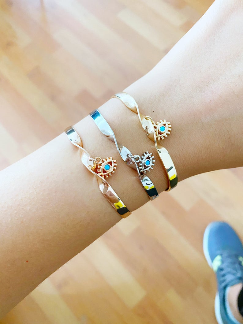 Elegant Evil Eye Cuff Bracelet in rose gold and silver, featuring a movable evil eye charm, crafted from tarnish-resistant stainless steel.