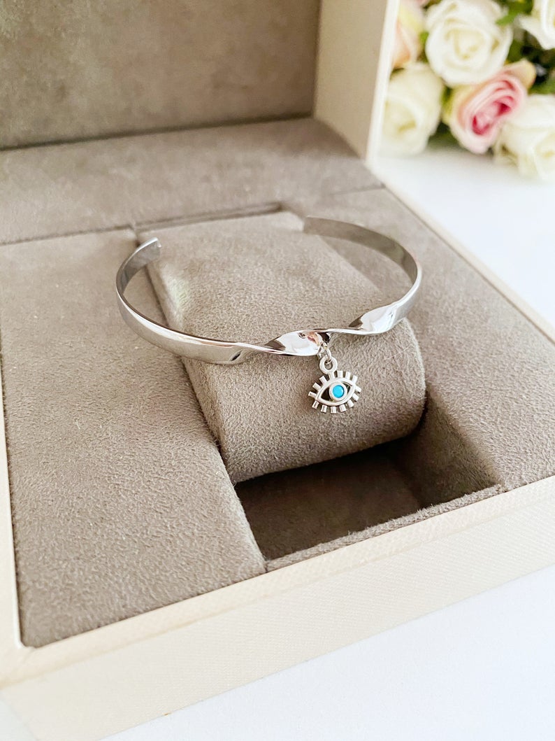 Elegant Evil Eye Cuff Bracelet in rose gold and silver, featuring a movable evil eye charm, crafted from tarnish-resistant stainless steel.