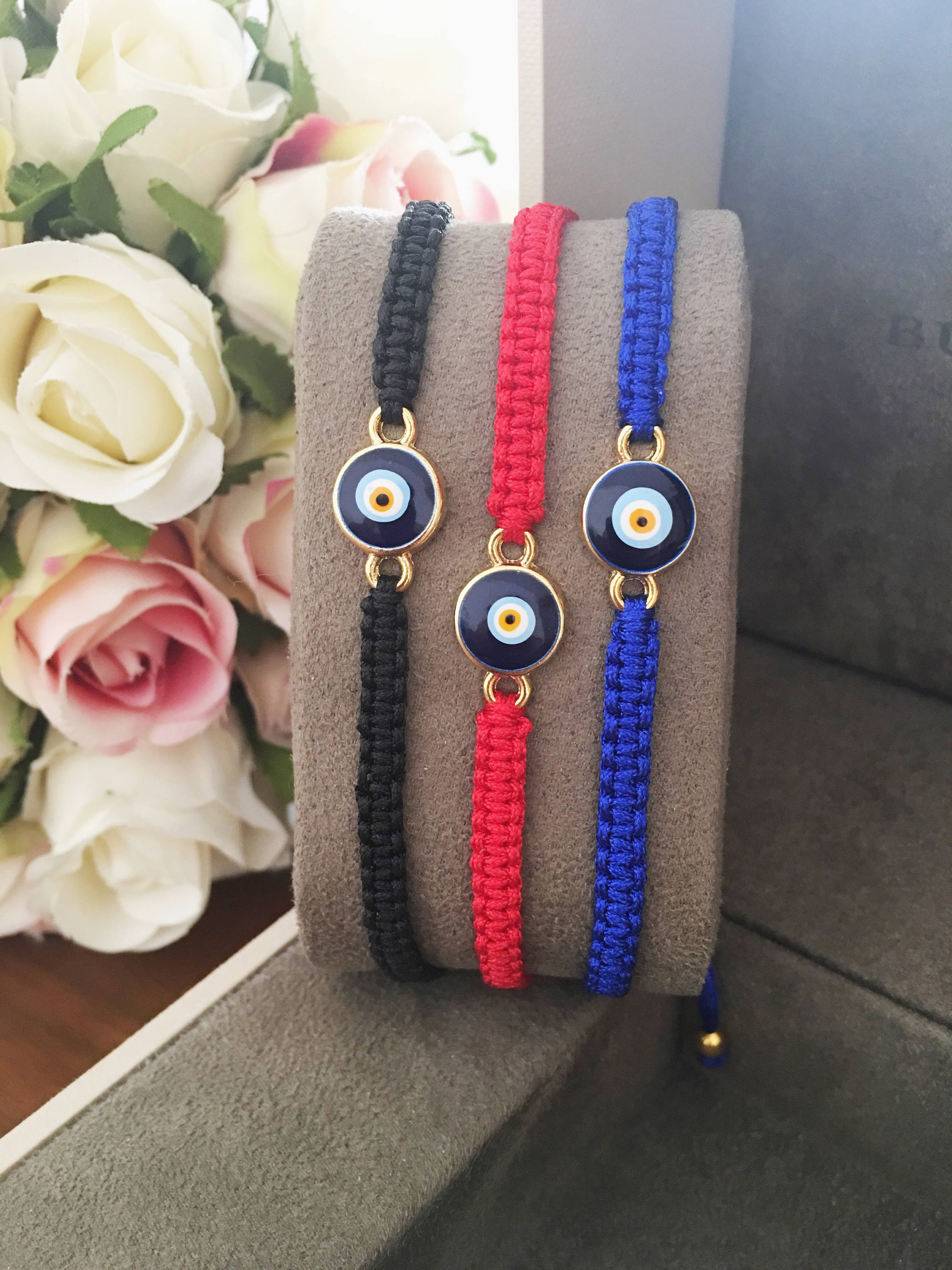 Handmade macrame evil eye bracelet in black, blue, and red strings, featuring a central evil eye charm for protection.