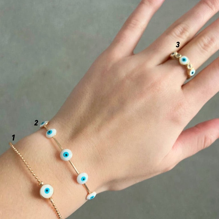 Handmade Evil Eye Jewelry including a white evil eye bracelet, cuff bracelet, and adjustable ring, symbolizing protection and luck.