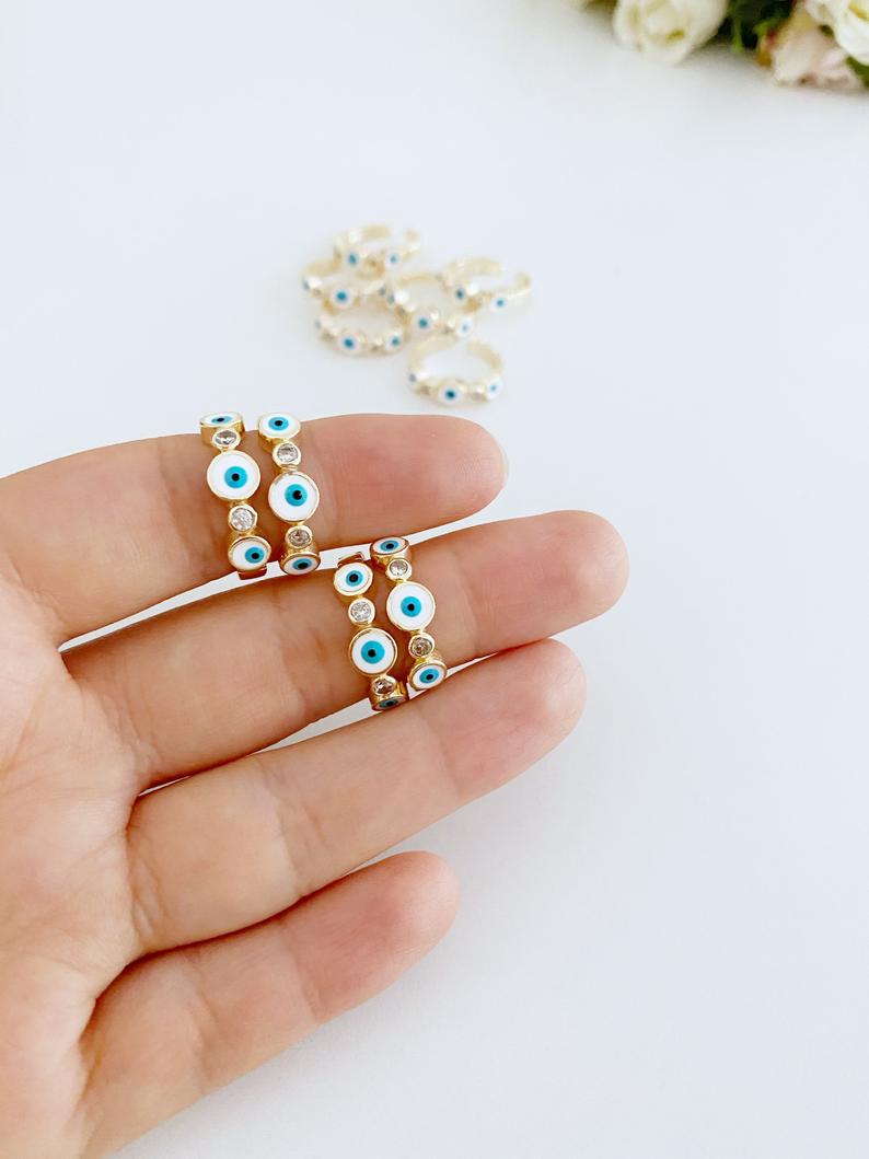 Handmade Evil Eye Jewelry including a white evil eye bracelet, cuff bracelet, and adjustable ring, symbolizing protection and luck.