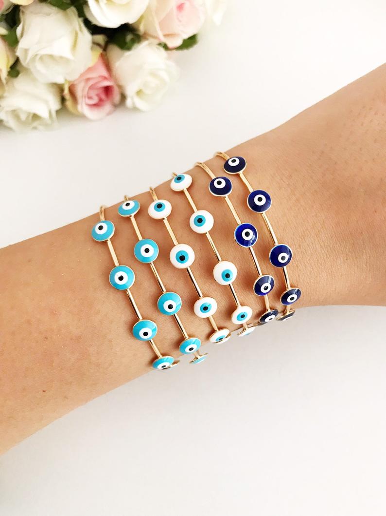 Handmade Evil Eye Jewelry including a white evil eye bracelet, cuff bracelet, and adjustable ring, symbolizing protection and luck.