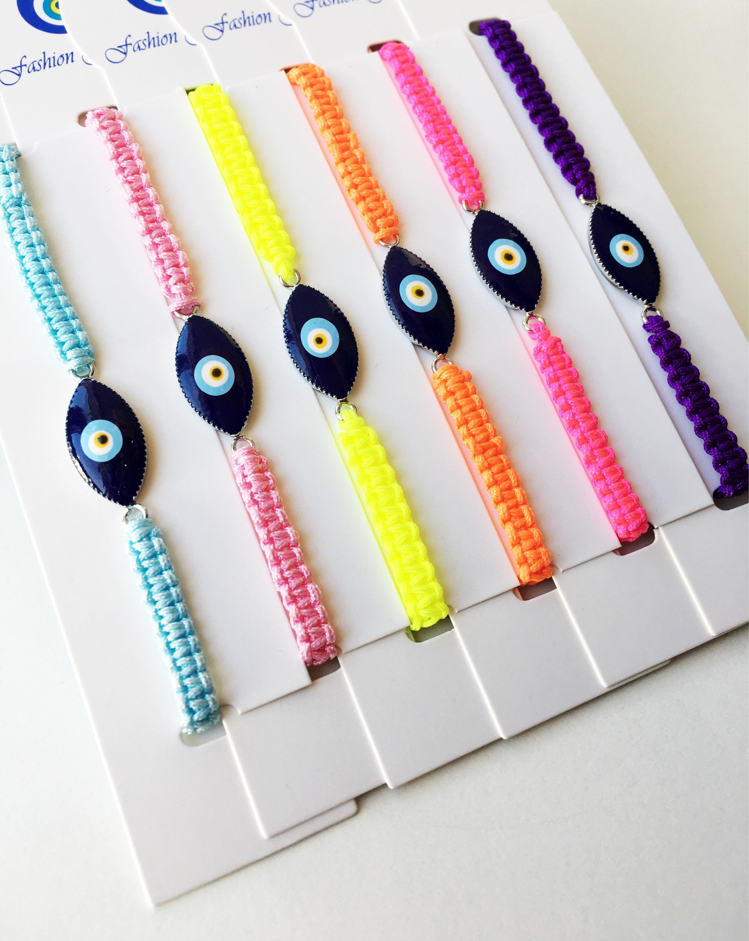 Evil Eye Macrame Bracelet featuring a black and white evil eye charm with colorful adjustable strings, handmade with intricate macrame design.