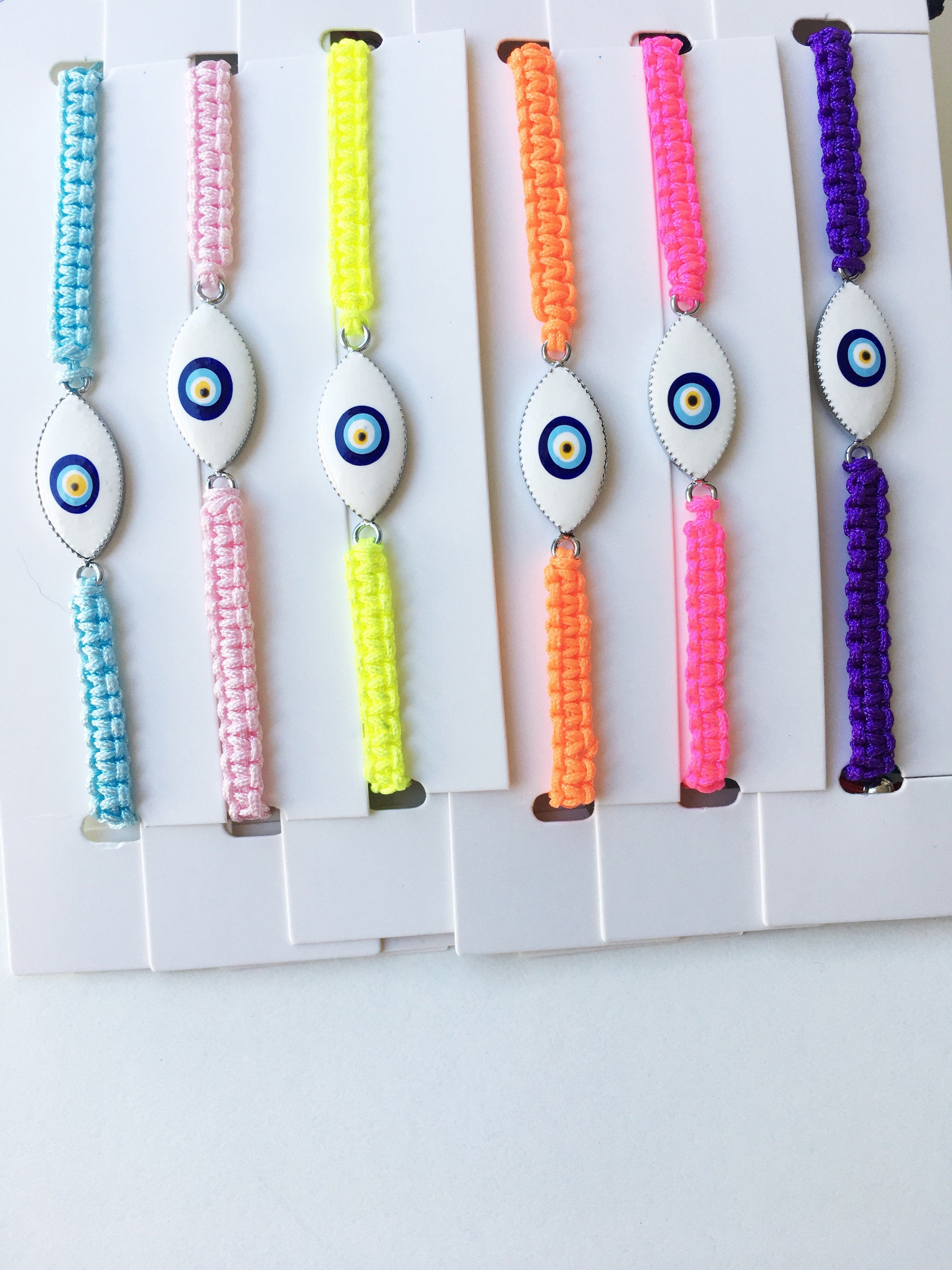 Evil Eye Macrame Bracelet featuring a black and white evil eye charm with colorful adjustable strings, handmade with intricate macrame design.