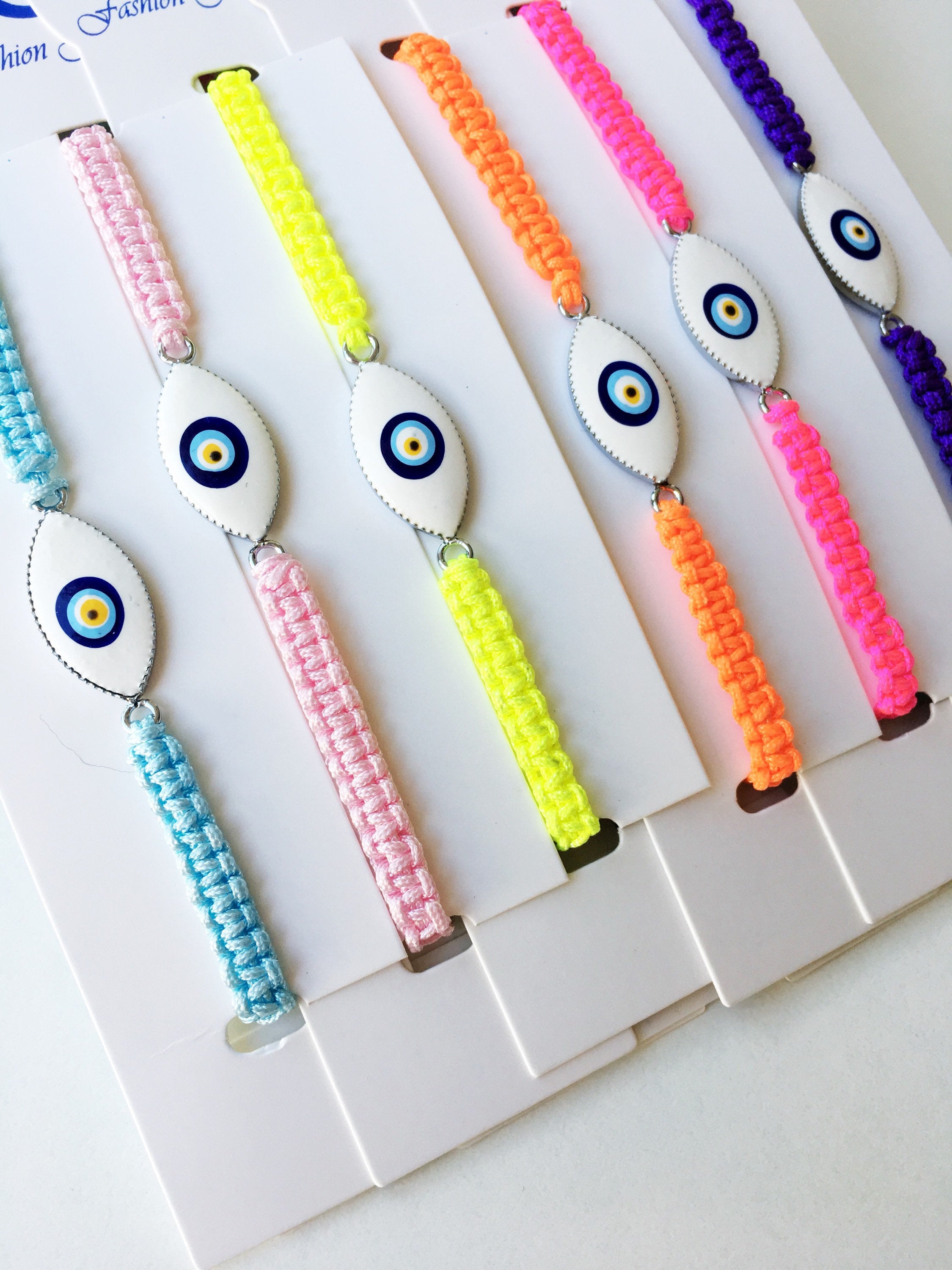 Evil Eye Macrame Bracelet featuring a black and white evil eye charm with colorful adjustable strings, handmade with intricate macrame design.