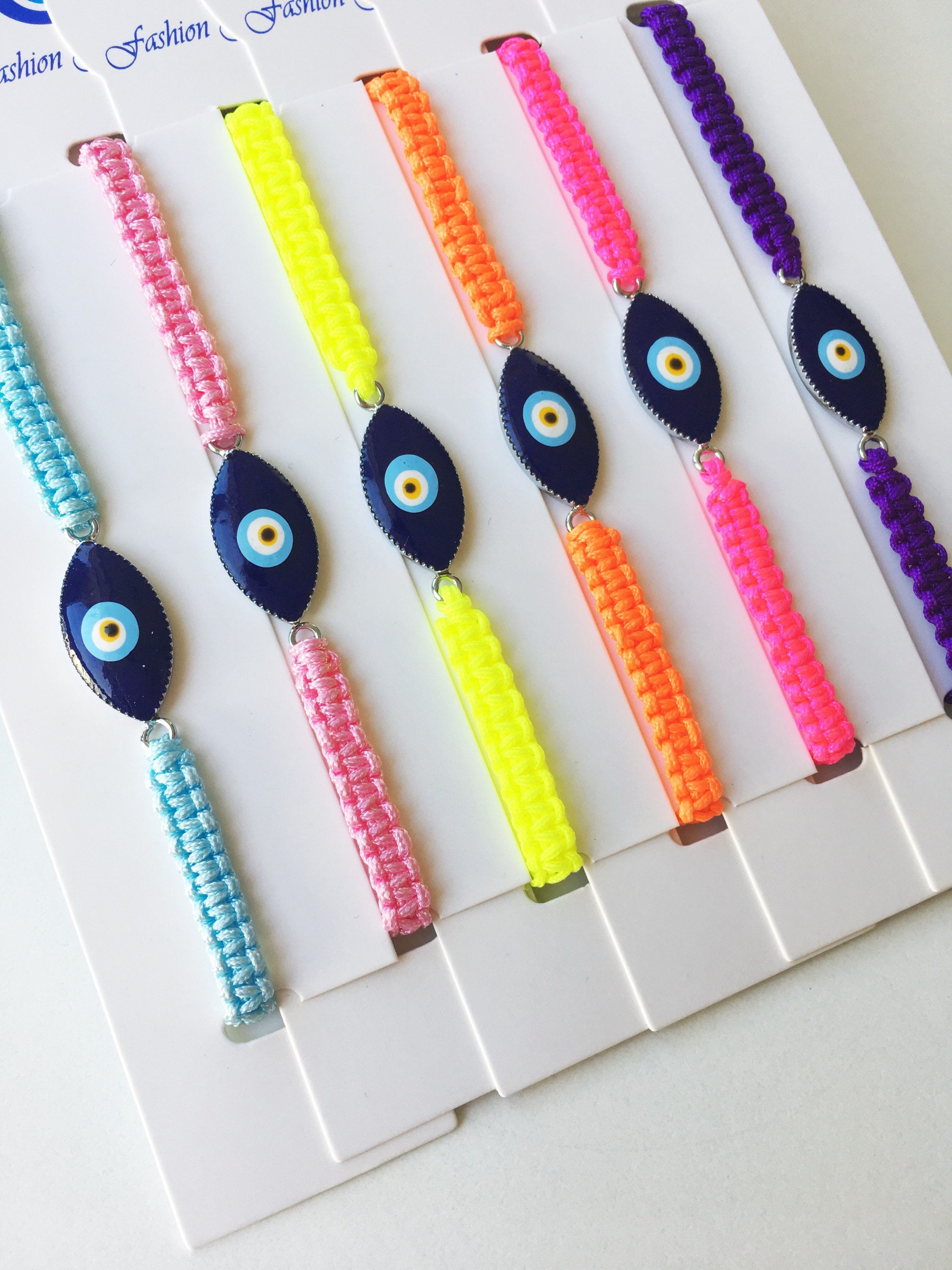 Evil Eye Macrame Bracelet featuring a black and white evil eye charm with colorful adjustable strings, handmade with intricate macrame design.