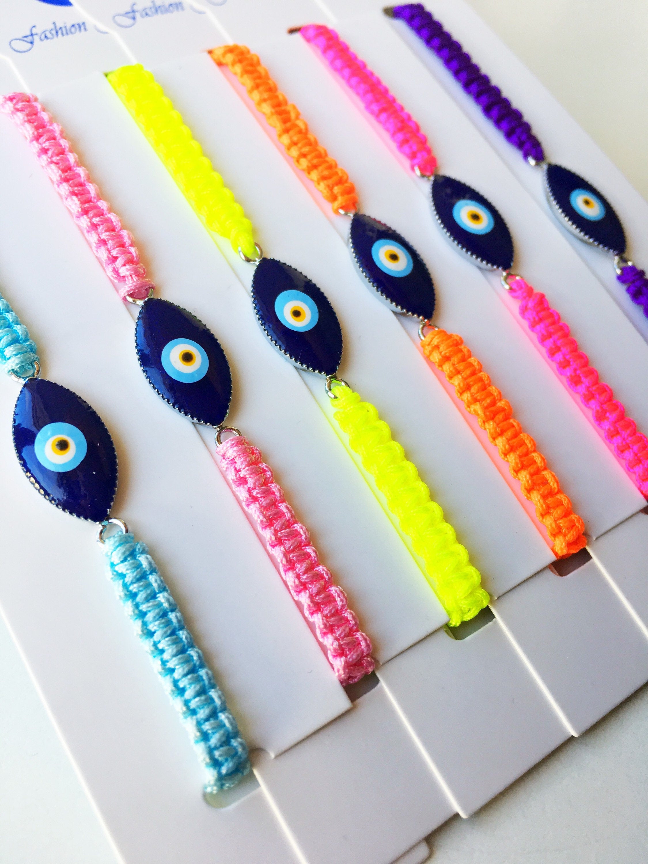 Evil Eye Macrame Bracelet featuring a black and white evil eye charm with colorful adjustable strings, handmade with intricate macrame design.