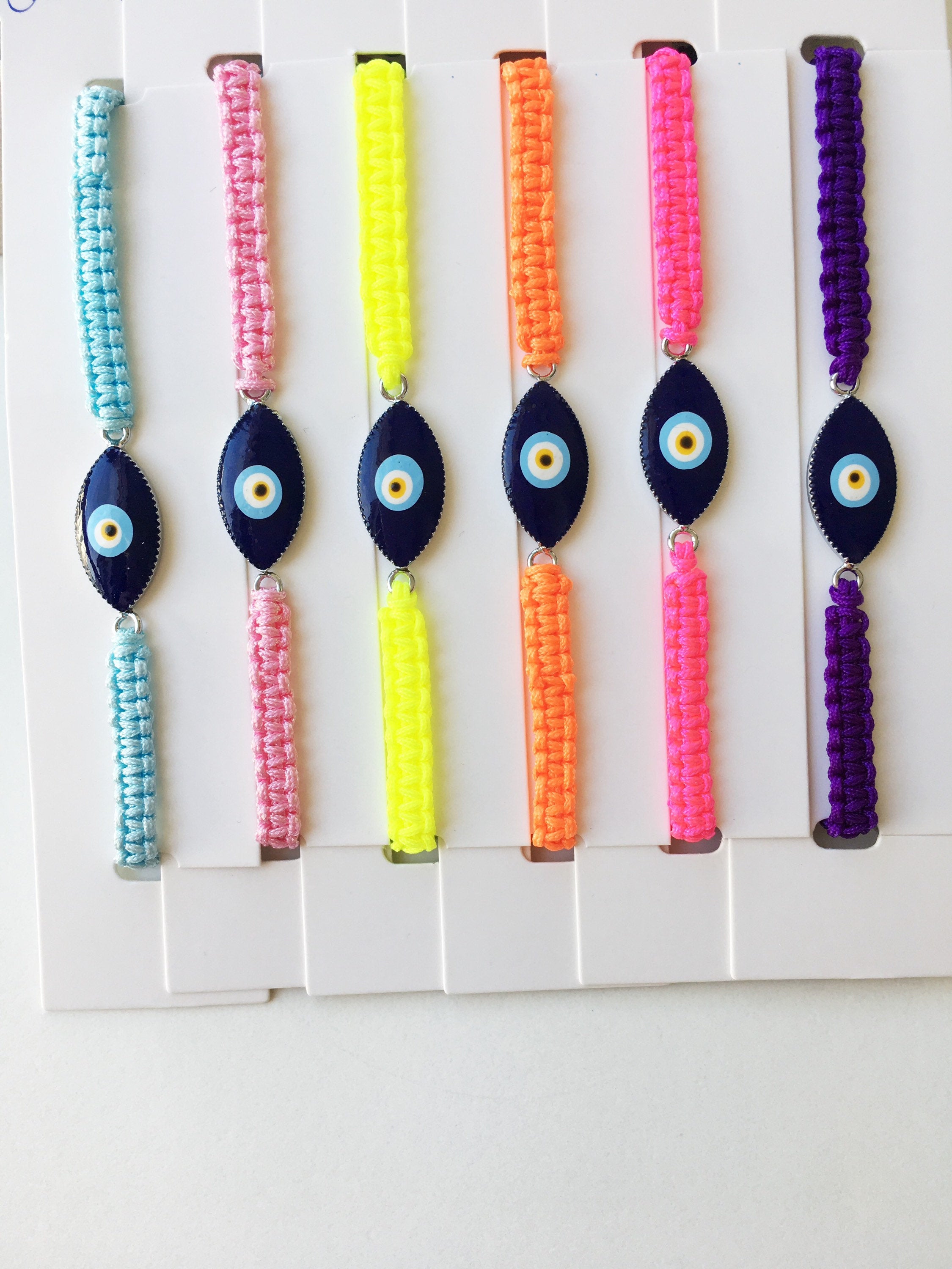 Evil Eye Macrame Bracelet featuring a black and white evil eye charm with colorful adjustable strings, handmade with intricate macrame design.