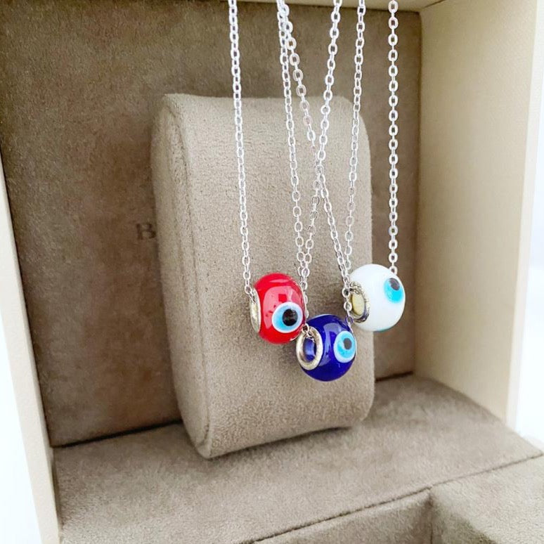 Evil Eye Murano Necklace featuring blue, red, and white charms on a silver stainless steel chain, symbolizing protection and style.