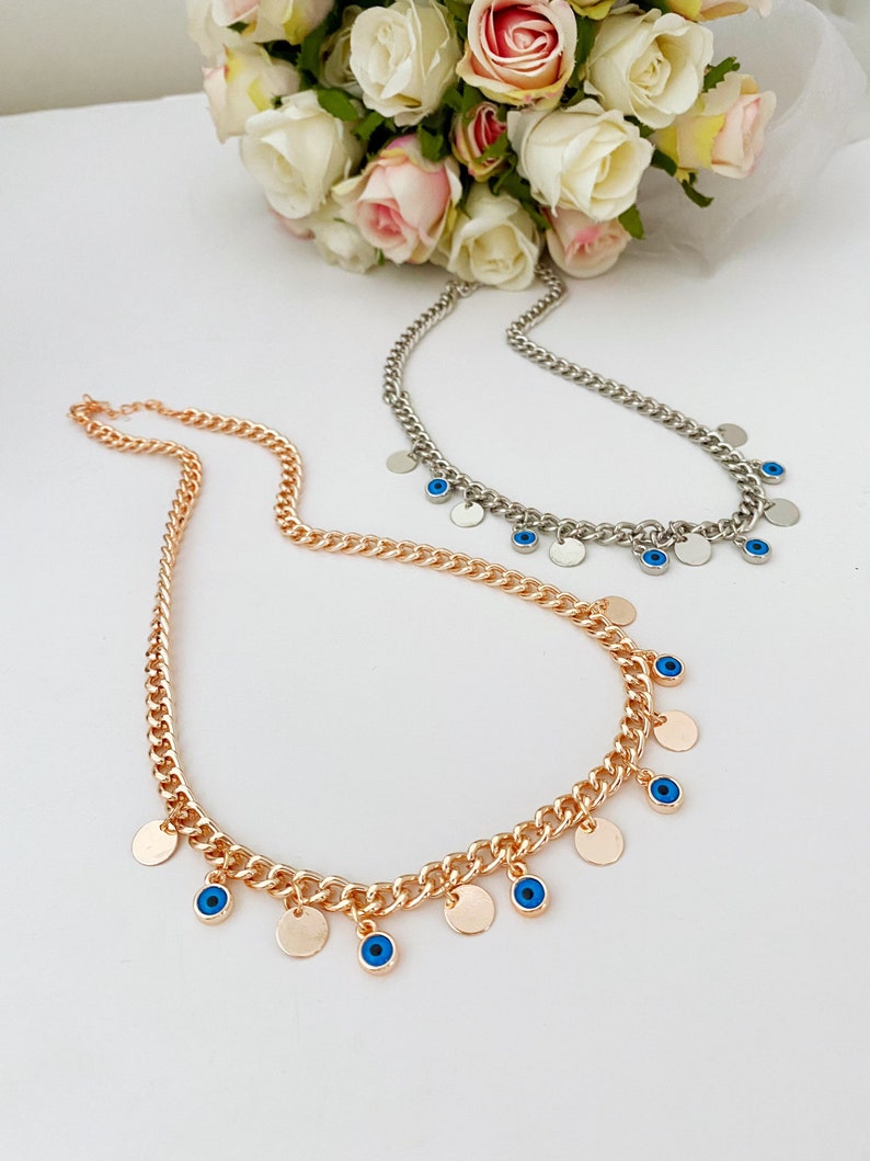 Handmade Evil Eye Necklace featuring a curb Cuban chain in silver and gold with tiny glass evil eye beads and gold-plated charms.