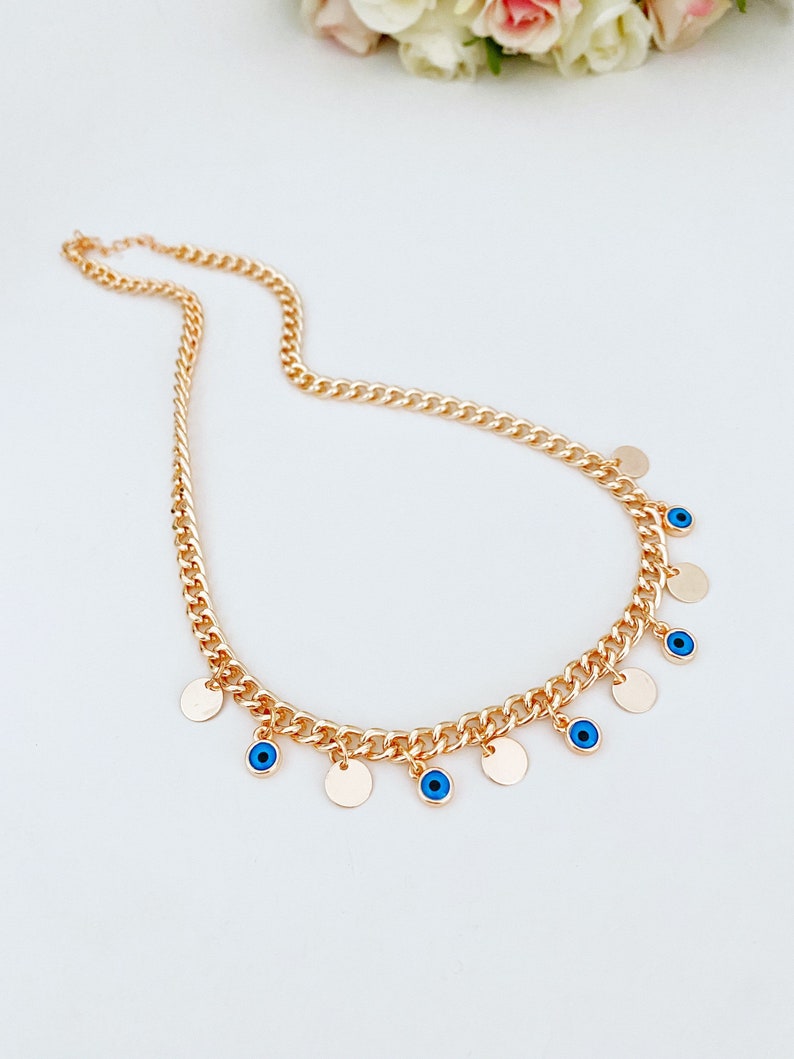 Handmade Evil Eye Necklace featuring a curb Cuban chain in silver and gold with tiny glass evil eye beads and gold-plated charms.