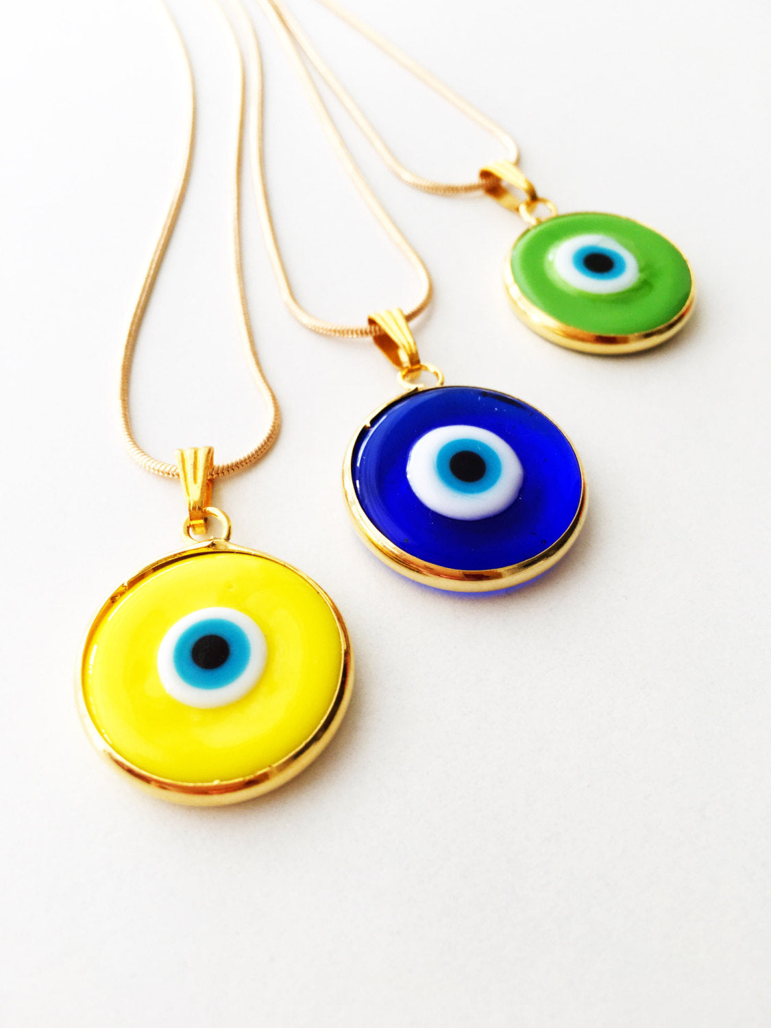 Elegant gold chain evil eye necklace with blue glass pendant, handmade with vibrant colors.