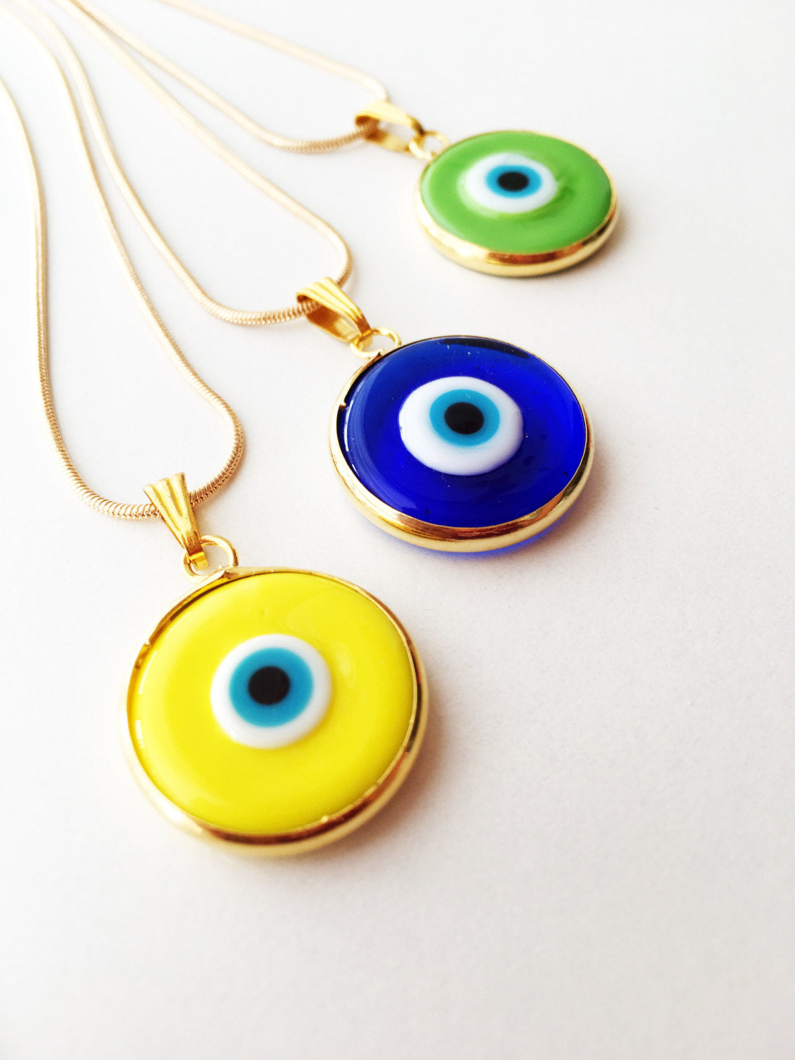 Elegant gold chain evil eye necklace with blue glass pendant, handmade with vibrant colors.