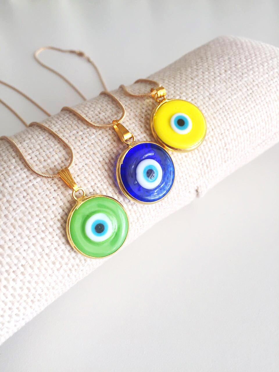 Elegant gold chain evil eye necklace with blue glass pendant, handmade with vibrant colors.
