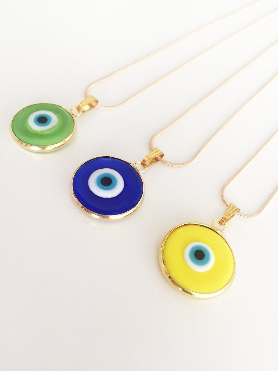 Elegant gold chain evil eye necklace with blue glass pendant, handmade with vibrant colors.