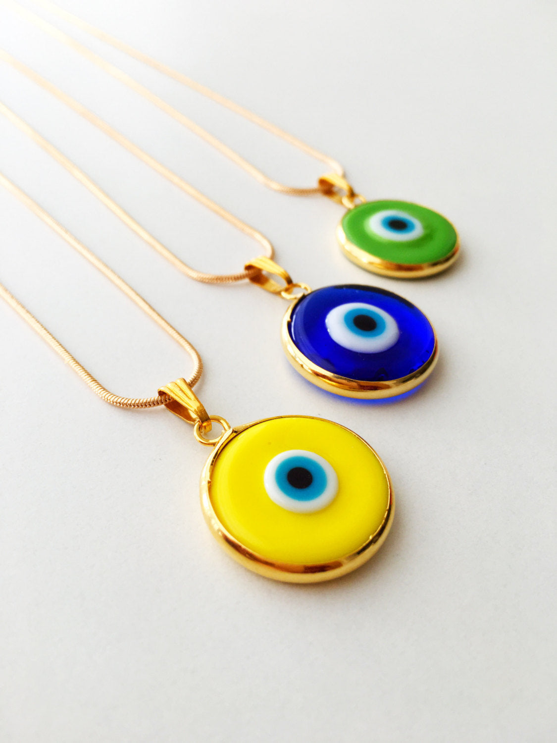 Elegant gold chain evil eye necklace with blue glass pendant, handmade with vibrant colors.