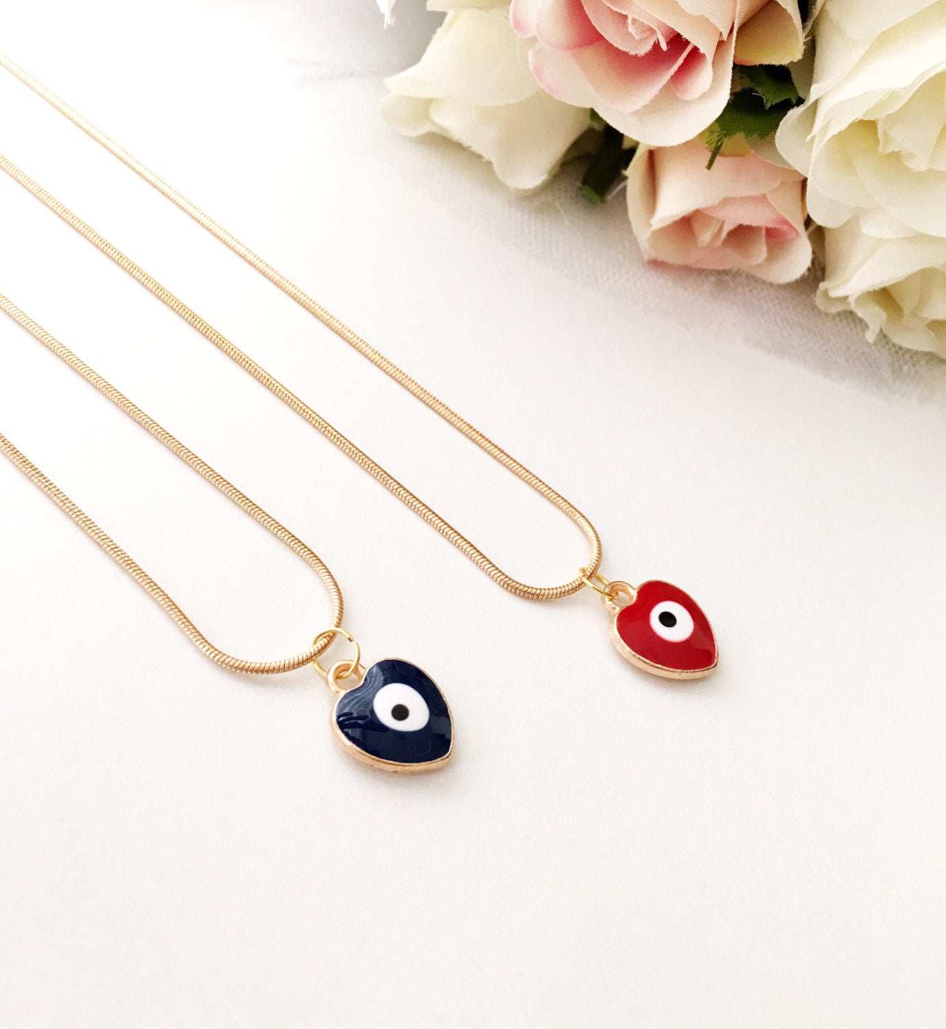 Handmade evil eye necklace featuring a heart charm in red and dark blue enamel with a 22K gold plated chain.